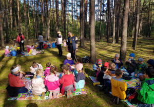 dzieci w lesie siedzą na matach podczas pikniku